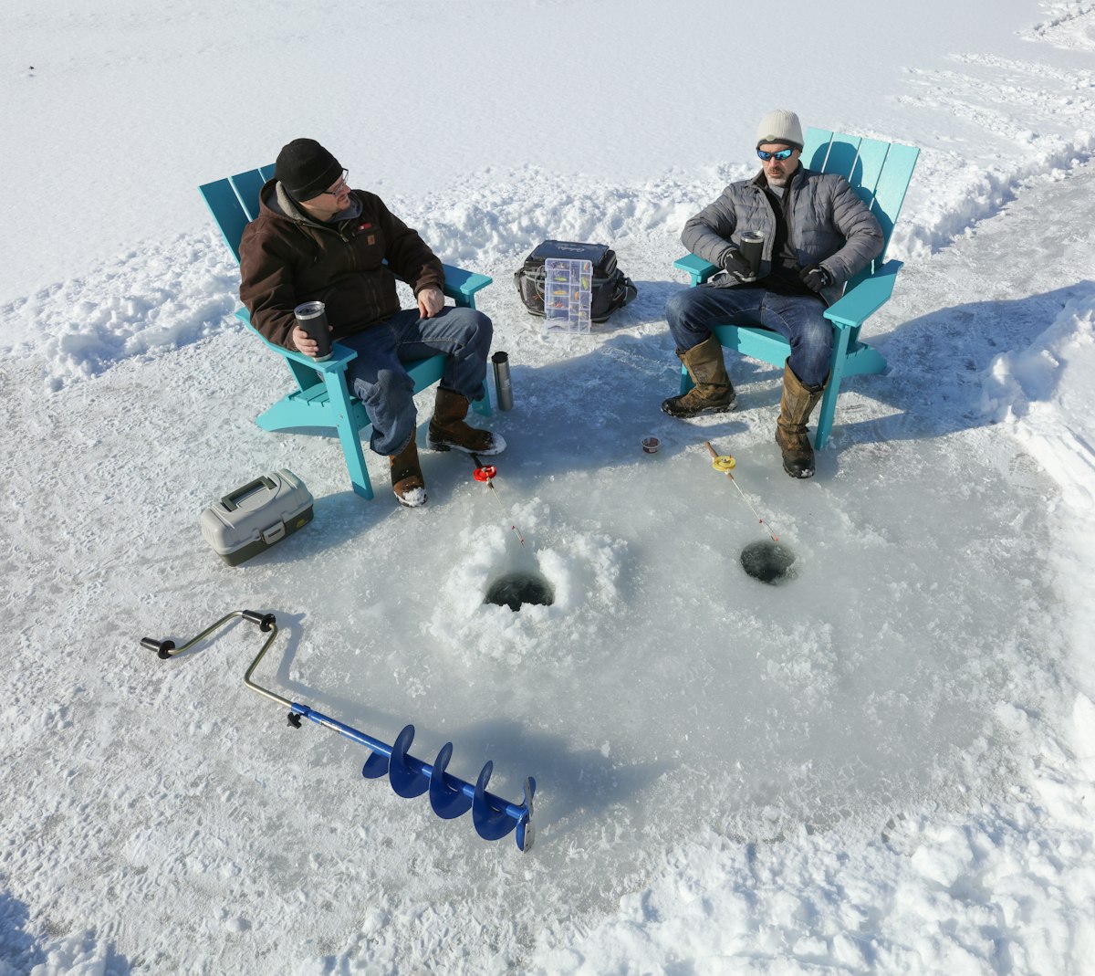 Two men ice fishing through holes on frozen lake